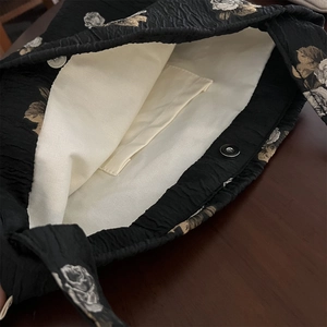 Interior detail of black floral jacquard bag with magnetic buckle and inner pocket
