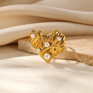 Detailed close-up of a golden textured heart ring with pearls on a stone base