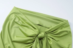 Detailed view of the grass green knotted fabric with subtle sheen and elastic texture