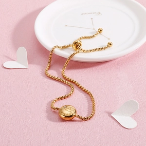 Macro detail of gold Sagittarius zodiac bracelet with adjustable chain on pink texture