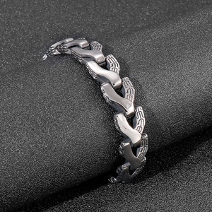 Macro detail of men's stainless steel dragon bone bracelet with woven textured metal links