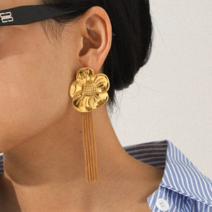 Close-up of model wearing 18k gold stainless steel floral earrings with long chain tassels