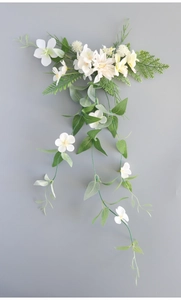 Detail of hanging artificial bridal flowers with white silk petals and green vine leaves
