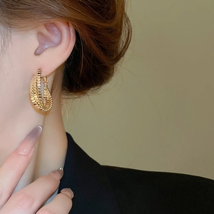 Detail shot of golden multi-layered textured hoop earrings worn by a model