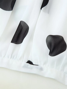 Makroaufnahme von weißem Chiffonstoff mit schwarzen Punkten und Plisseesaum-Detail