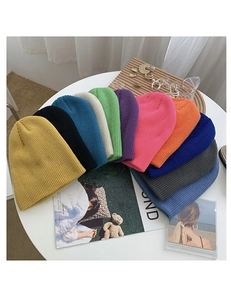 Flat lay of colorful thick knitted beanies in eleven vibrant shades for autumn and winter