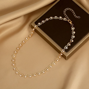 Detail of gold heart link necklace with white pearls on a luxury silk background