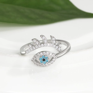Makro-Detail von silbernem Evil-Eye-Ring mit blauen Steinen und schimmernden Wimpern