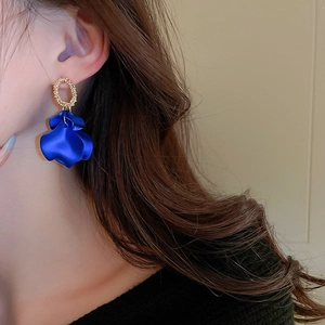 Close-up of elegant gold textured hoop earrings with deep blue fabric petal drops