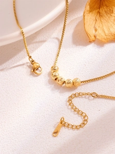 Detailed macro of gold box chain featuring five textured beads and lobster clasp closure