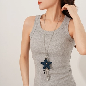 Detail of star-shaped denim necklace pendant with floral accent and charms on silver chain