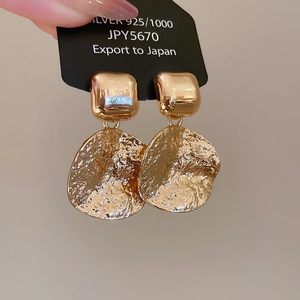 Macro shot of 925 silver golden geometric earrings with hammered metal texture details
