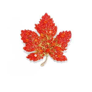 Elegant maple leaf brooch with red and orange crystals on gold-toned metal base