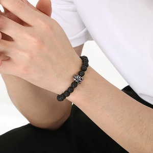 Detail of 8mm black volcanic stone beads and silver skull charm on men's elastic bracelet