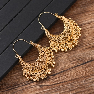 Détail de boucles d'oreilles géométriques dorées avec glands en style bohème vintage