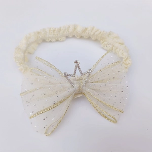 Detail of baby lace headband with large beige glittery mesh bow and silver crown