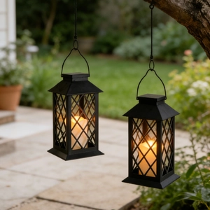 Detail of two vintage hanging lanterns with LED candles displayed in a garden setting
