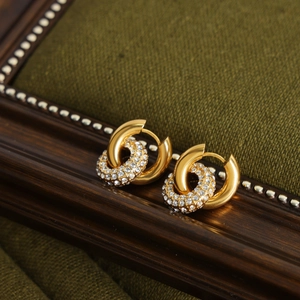 Détail macro de boucles d'oreilles double cercle dorées avec zircons brillants de luxe