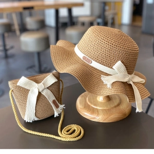 Detail of khaki straw sun hat and matching bag with elegant white ribbon bows