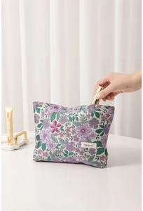 Detail of floral jacquard makeup bag with purple flower embroidery and H&R brand label