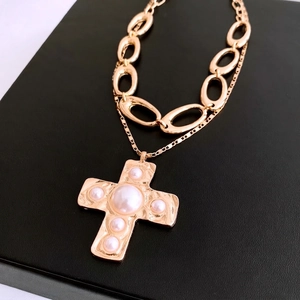 Baroque style gold double layer cross necklace with vintage pearls on black leather background
