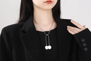 Detail of silver Y-shaped snake chain necklace with dual round pendants on model