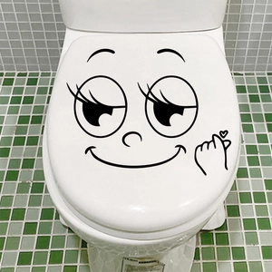 Detail of funny cartoon smiling face and finger heart decal on a white toilet lid