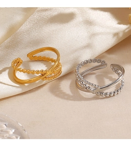 Detail of gold and silver beaded crossover open rings on a cream satin fabric background