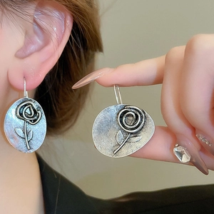 Detailed view of vintage silver flower earrings with embossed rose patterns for women