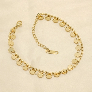 Cavigliera doppia in acciaio inossidabile dorato con perline e dischi su tessuto beige