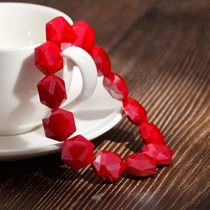 Close-up of red geometric faceted crystal beads wrapped around a white coffee cup handle
