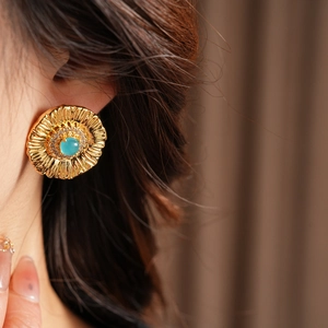 Macro shot of vintage gold flower earring with turquoise center and sparkling crystals