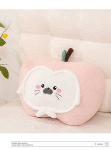 Macro detail of pink apple plush pillow with cute seal face embroidery and leaf accent