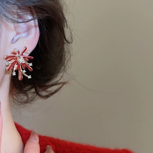 Detail view of red firework stud earrings with gold plating on female model