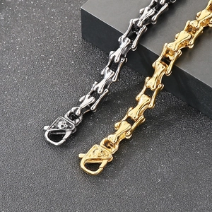 Detail of punk style skull clasp on gold and silver bone-shaped link bracelets