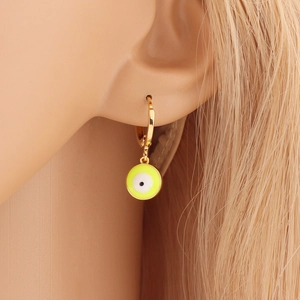 Close-up of gold hoop earrings with yellow-green enamel evil eye charm on model