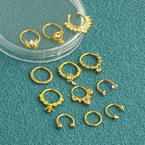 Macro shot of gold-plated nose and cartilage rings with zircon inlays on blue texture
