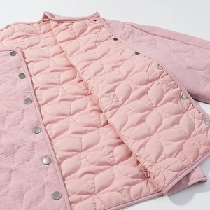 Close-up of pink quilted jacket lining showing diamond stitching and metal snap buttons
