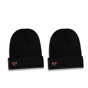 Two black knitted beanies with orange heart embroidery on a clean white background