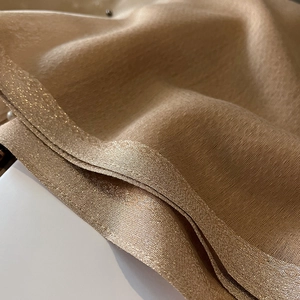 Detail of champagne gold silk scarf with metallic threads and luxury drape texture