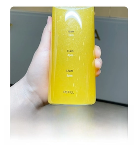 Detail of transparent water bottle with time markers and orange juice held by hand