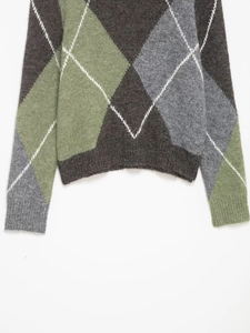 Detailed close-up of argyle knit sweater hem showing grey and green diamond texture