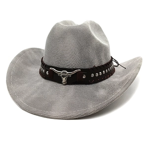 Detail of western cowboy straw hat featuring a bull head buckle and silver metal rivets