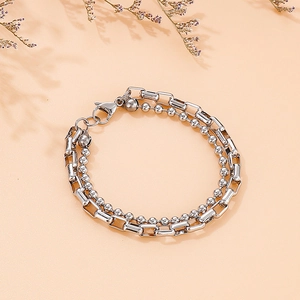 Detail of silver double-layer bracelet with bead and box chains on peach background