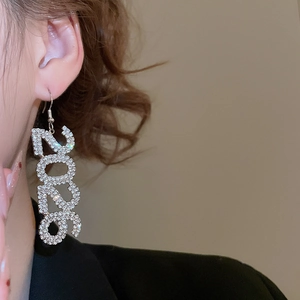 Primo piano di orecchini scintillanti color argento numero 2026 con strass indossati