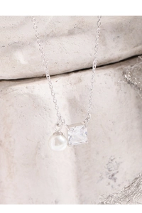 Macro shot of silver S925 necklace featuring a square zircon and white pearl pendant