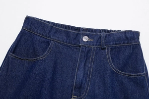 Detail of dark blue denim shorts featuring an elastic waistband and silver button