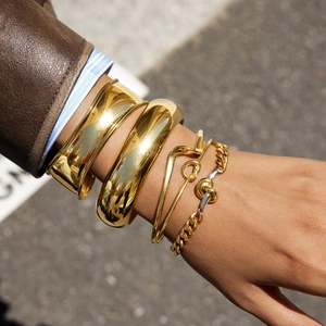 Bracelets et chaînes empilés en acier inoxydable plaqué or 18k portés par un modèle