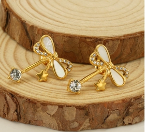 Detailed macro view of gold bow earrings with white mother of pearl and crystal stars