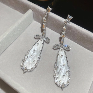 Detail of silver drop earrings with zircon bow and pearlescent teardrop pendant